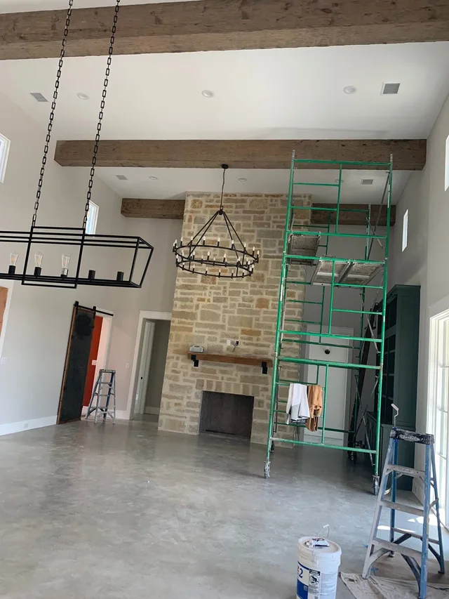 Freshly painted living room with exposed beam ceiling and chandeliers