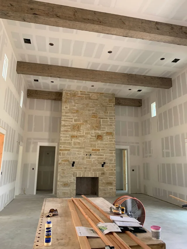 Unfinished living room with bare drywall and stone fireplace