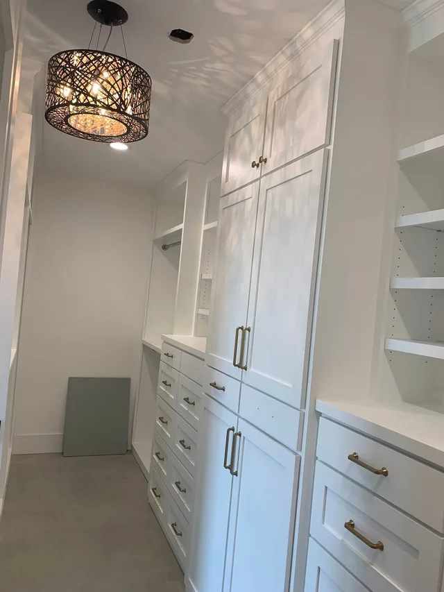 Crisp white built-in closet cabinets with gold hardware