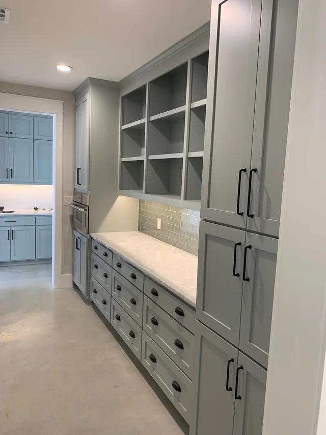 Sage green butler's pantry cabinets with open shelving and subway tile